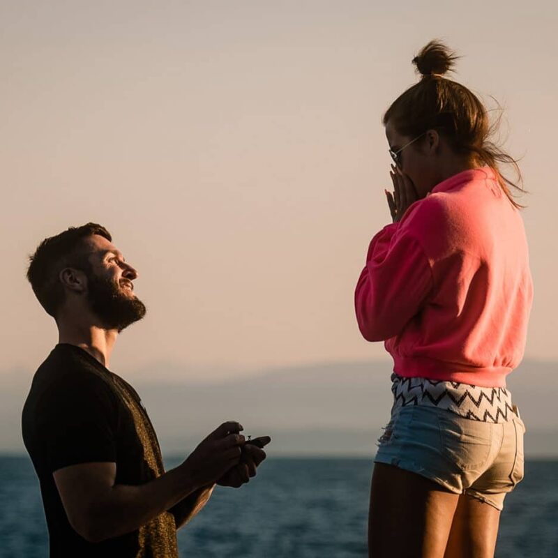 surprise proposal with Fresh Air Photography in Sechelt BC. Man kneels by the ocean and presents a ring to his lady
