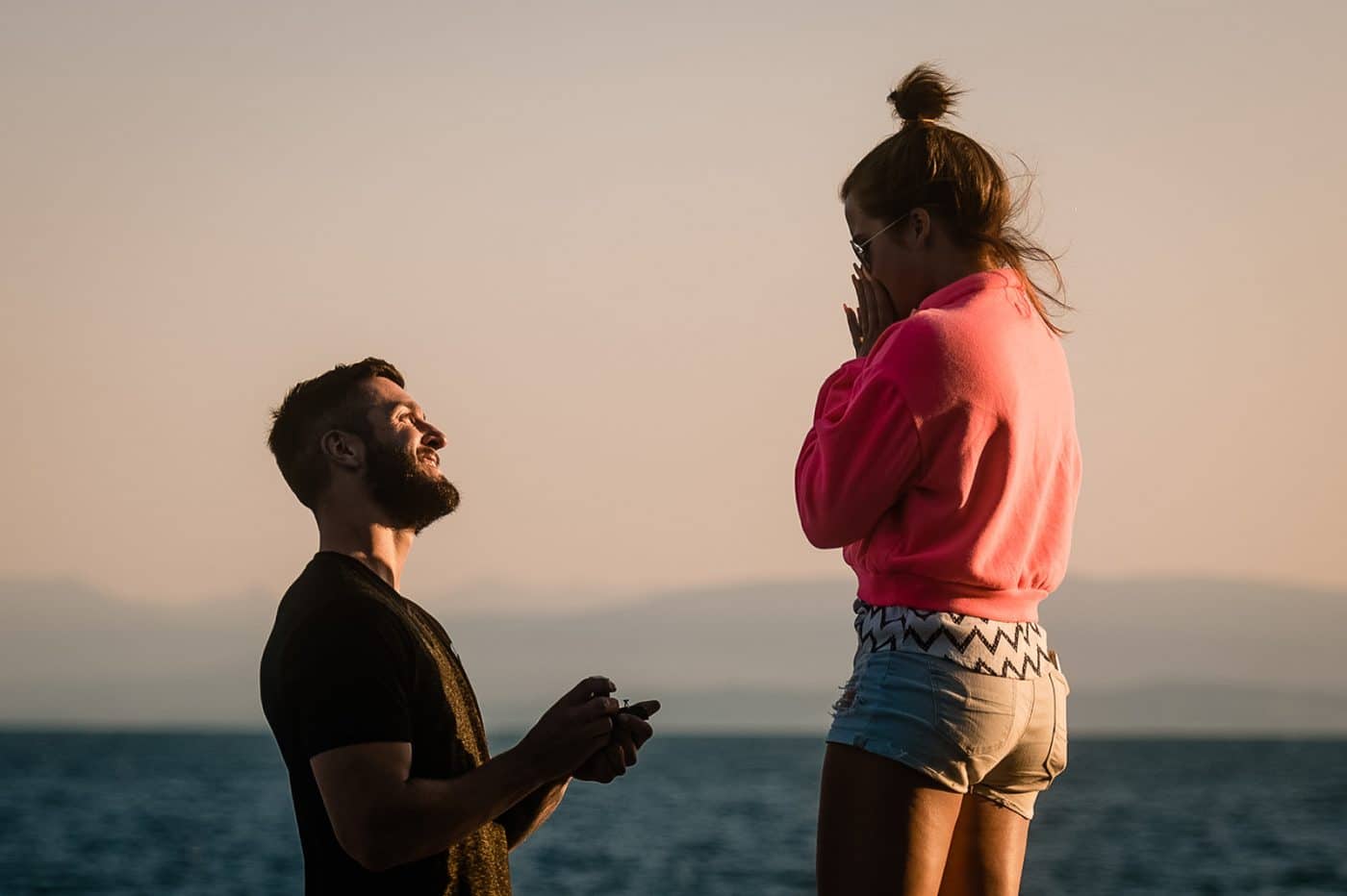 surprise proposal with Fresh Air Photography in Sechelt BC. Man kneels by the ocean and presents a ring to his lady