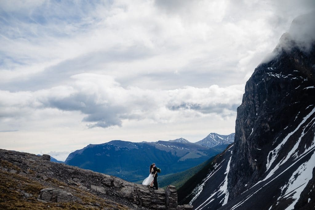 a newly eloped couple embrace where two mountain peaks meet during their adventure elopement in british columbia with bc adventure elopement photographer