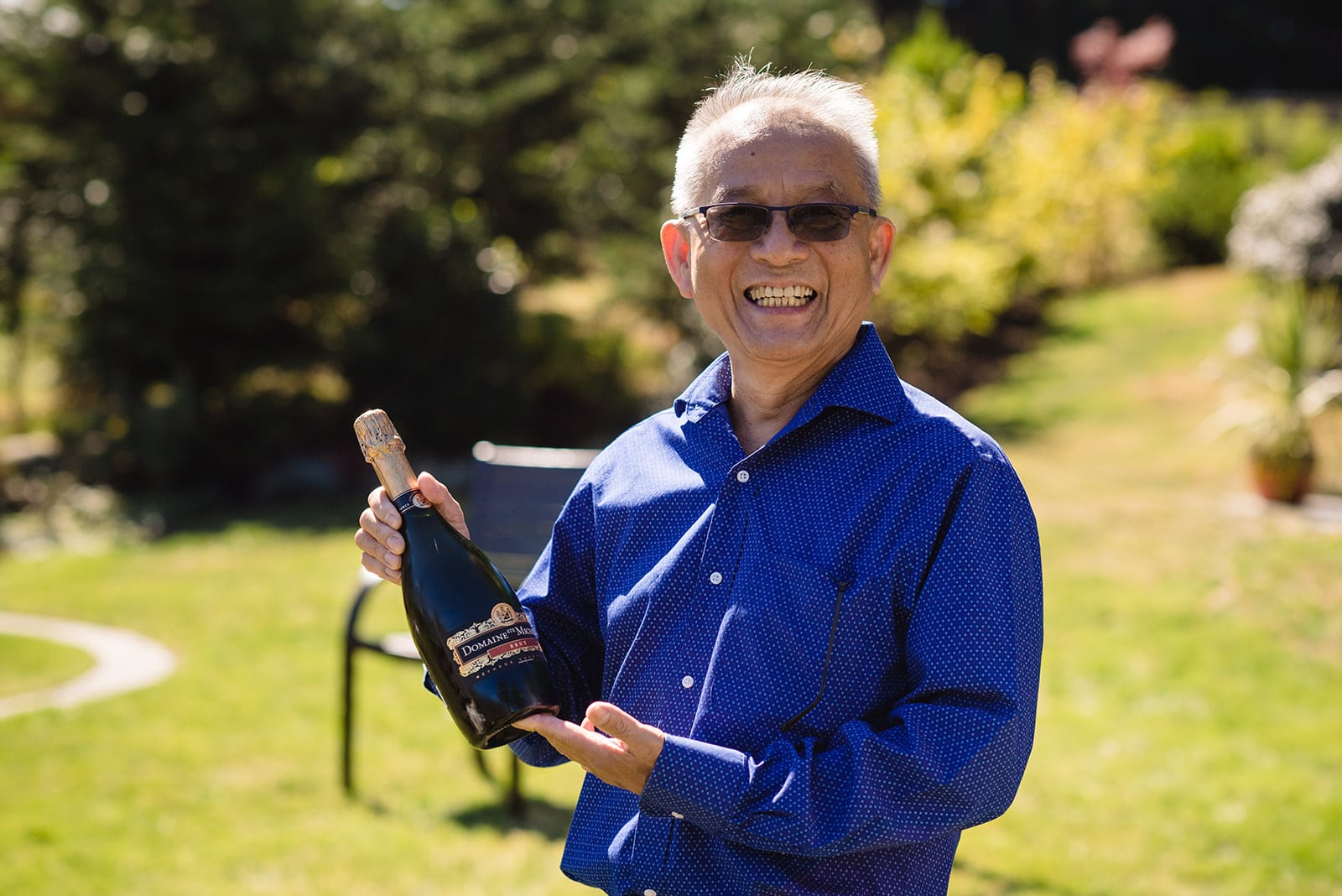 Father of the Bride shows the bottle of champagne that is needed to celebrate his daughter getting married on the Sunshine Coast BC
