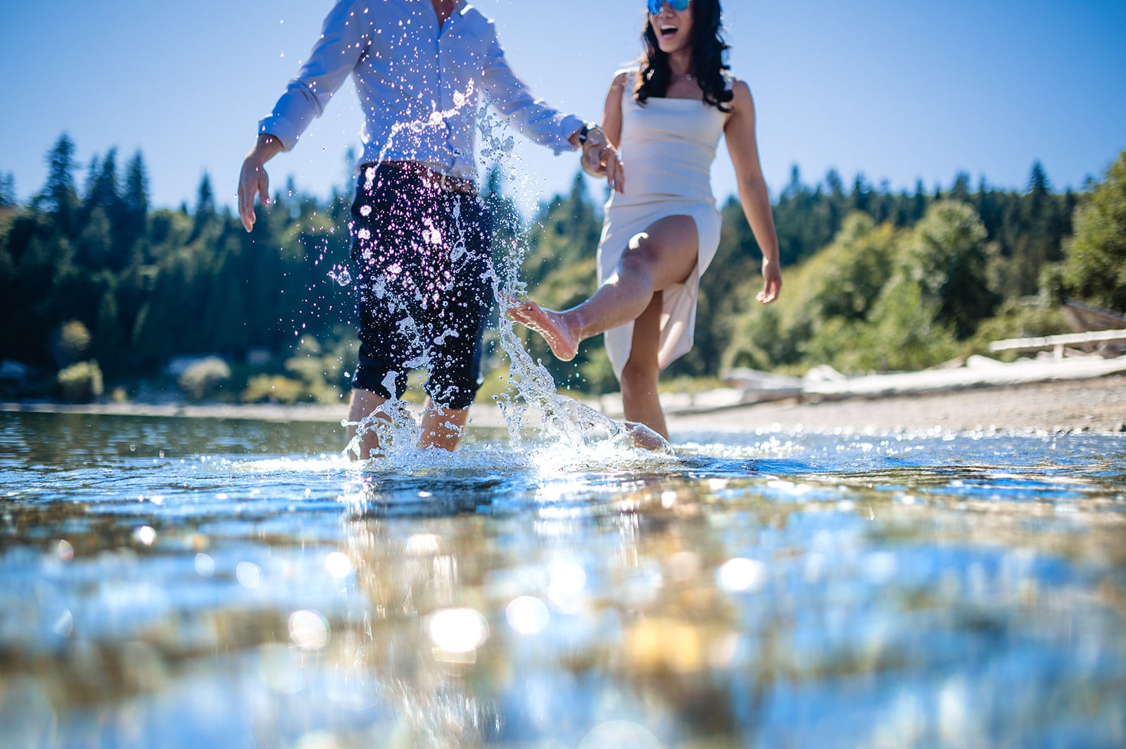 bride and groom splash knee high in the ocean with happiness