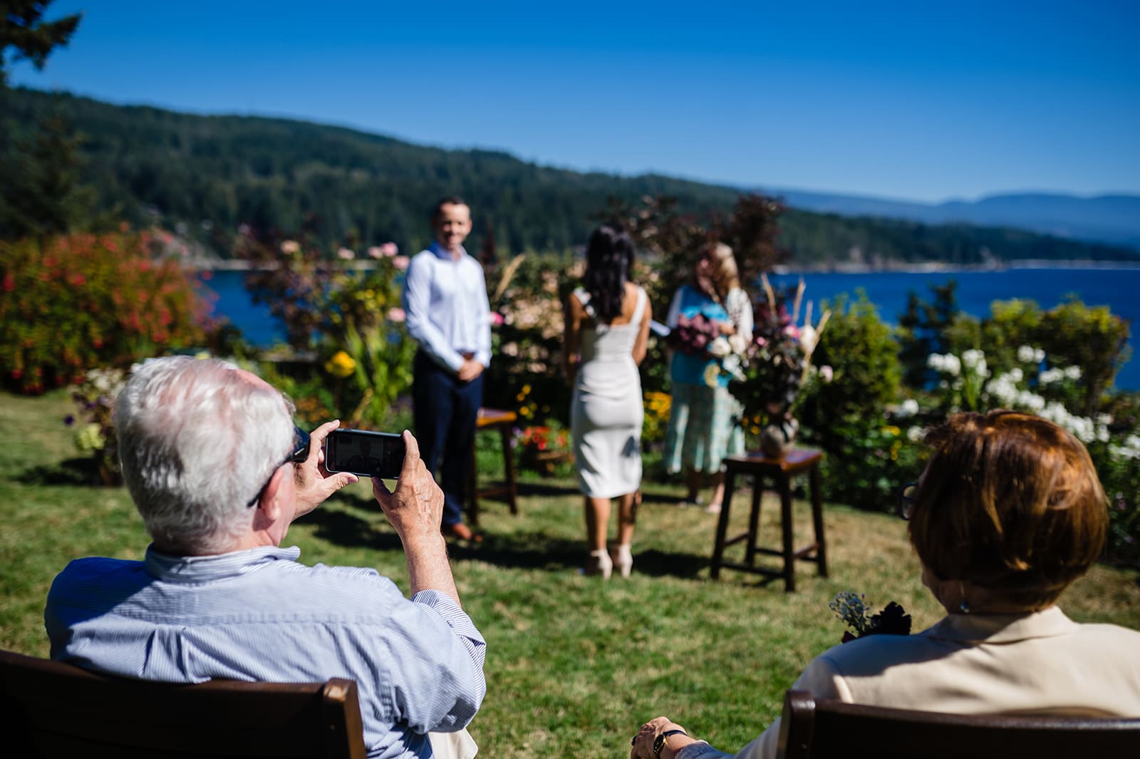 The father of the groom videos a wedding ceremony for family with his iphone, that cannot be there to attend due to Covid 19