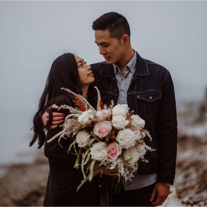 A young couple newly engaged pose for a portrait with a beautiful bouquet