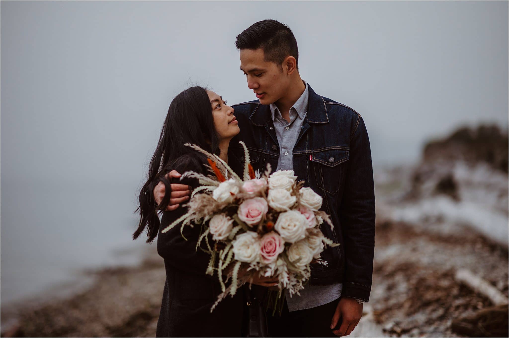 A young couple newly engaged pose for a portrait with a beautiful bouquet