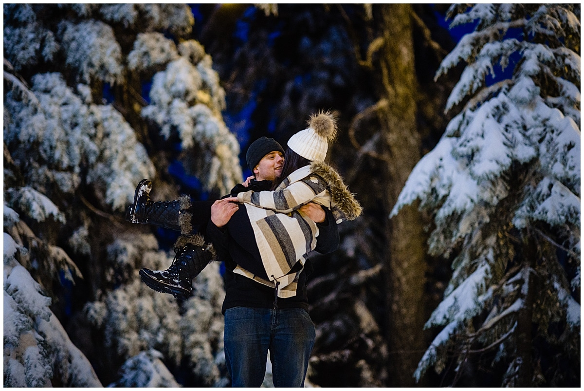 Kayla Reece surprise Proposal, Reece picks up his bride to be amongst the tall evergreens covered in snow