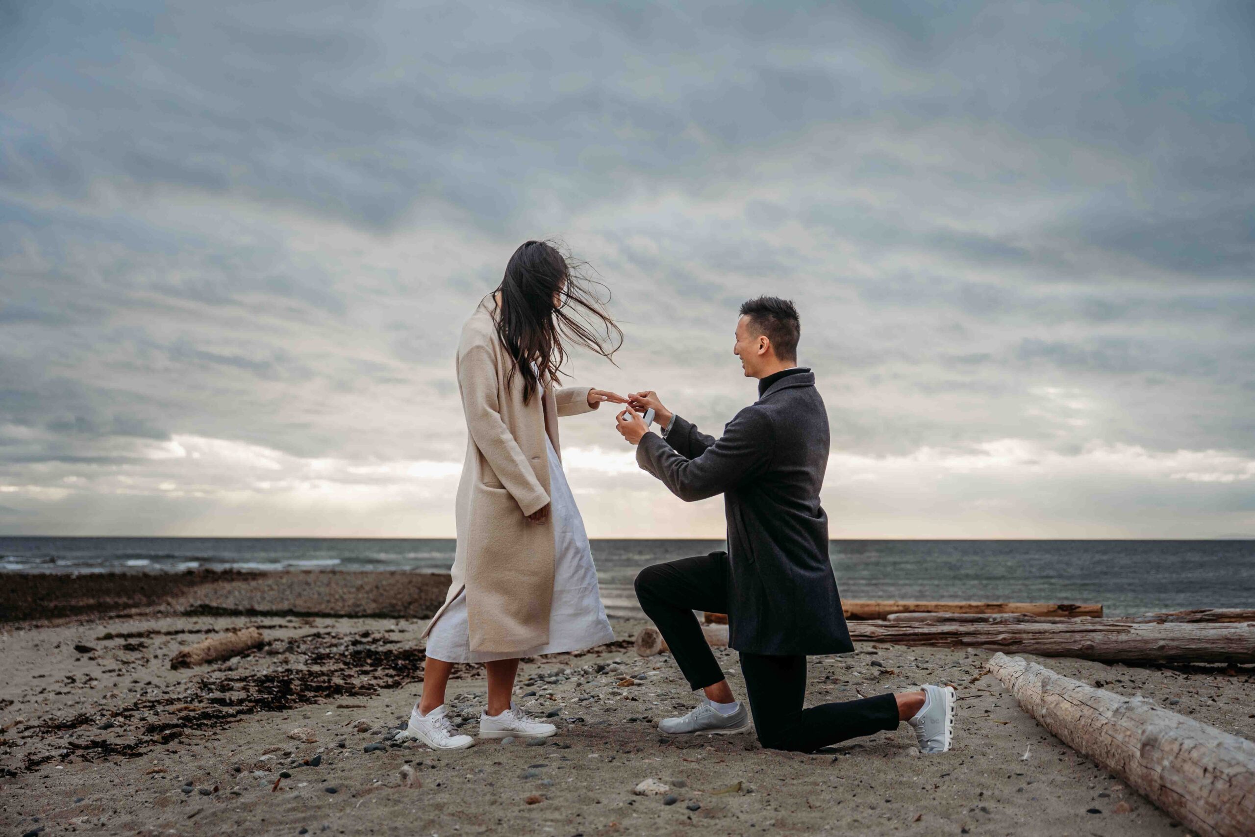 man proposing on his one knee to his partner on the sandy beach at Davis Bay on the Sunshine Coast BC
