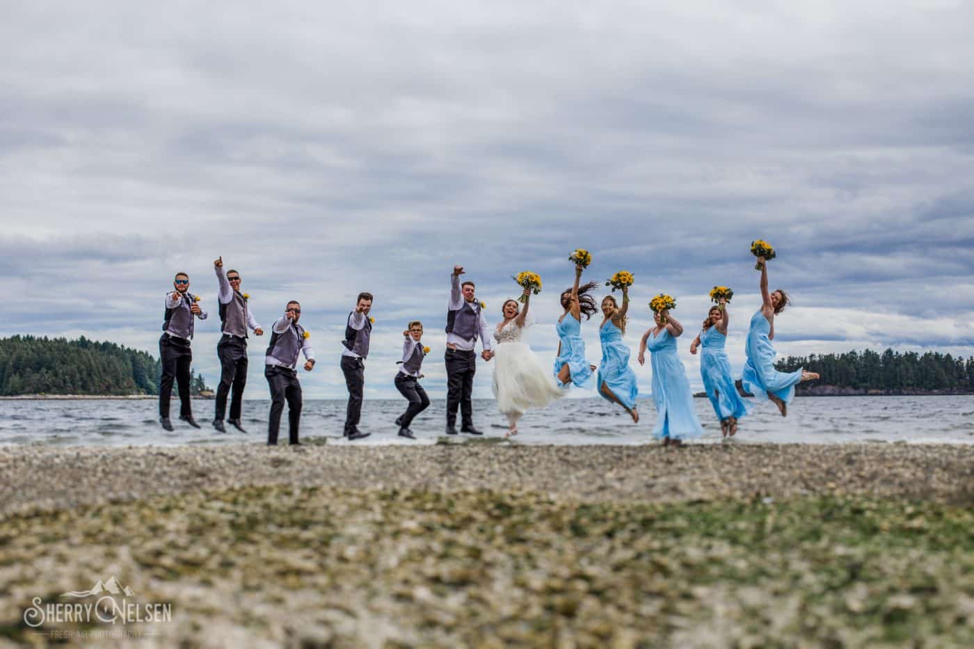 bride, groom and wedding party jump to celebrate their wedding on the beach
