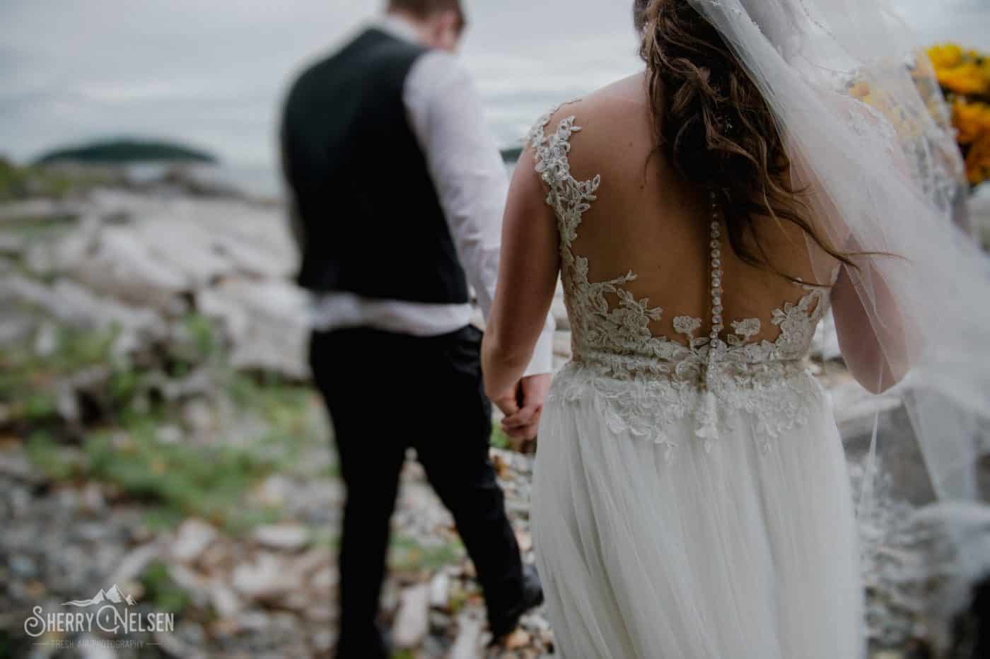 groom takes his bride by the hand to walk along the beach for portraits before they marry in Sechelt BC