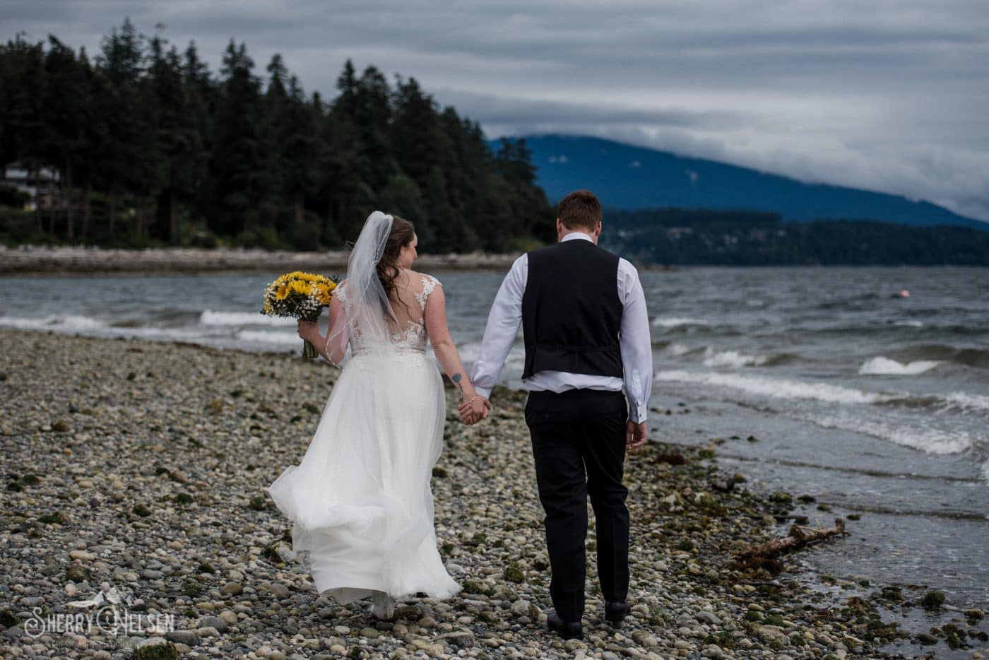 Shane and Shelbi's Sechelt wedding day included a walk along a stormy beach with her sunflower bouquet to brighten the day like sunshine