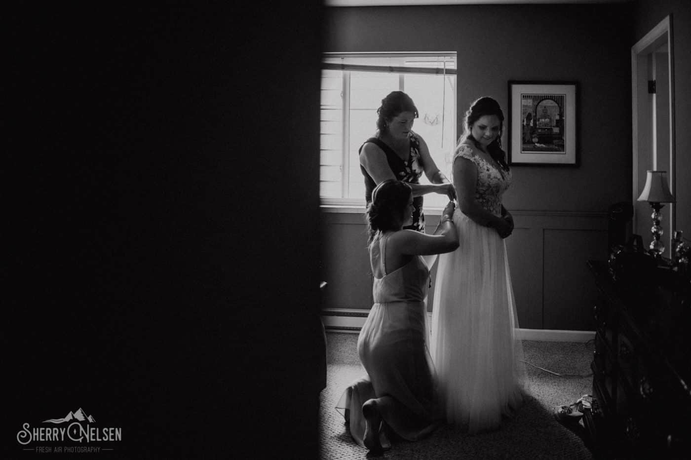 mom and sister help button the bride into her dress at a Sunshine Coast BC wedding