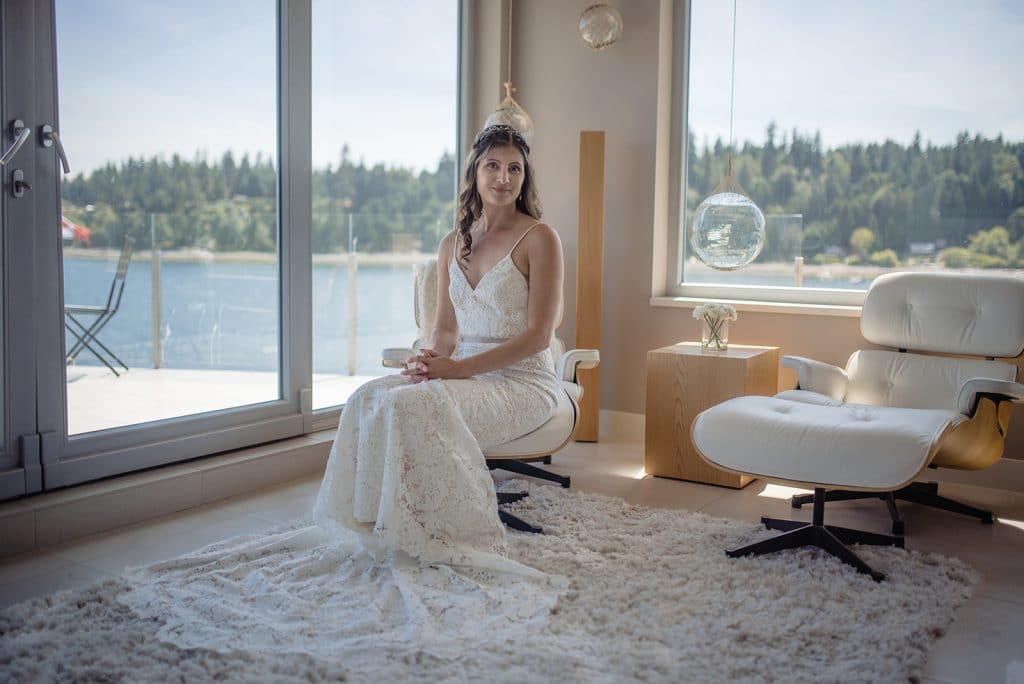 bride sits on chair in room overlooking the ocean