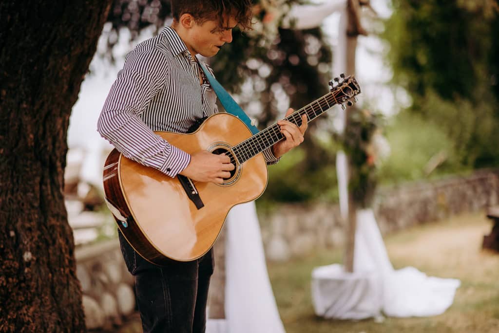 a guitar player strums his soft music as the bride walks down the aisle at Sunshine Coast wedding Gibsons BC