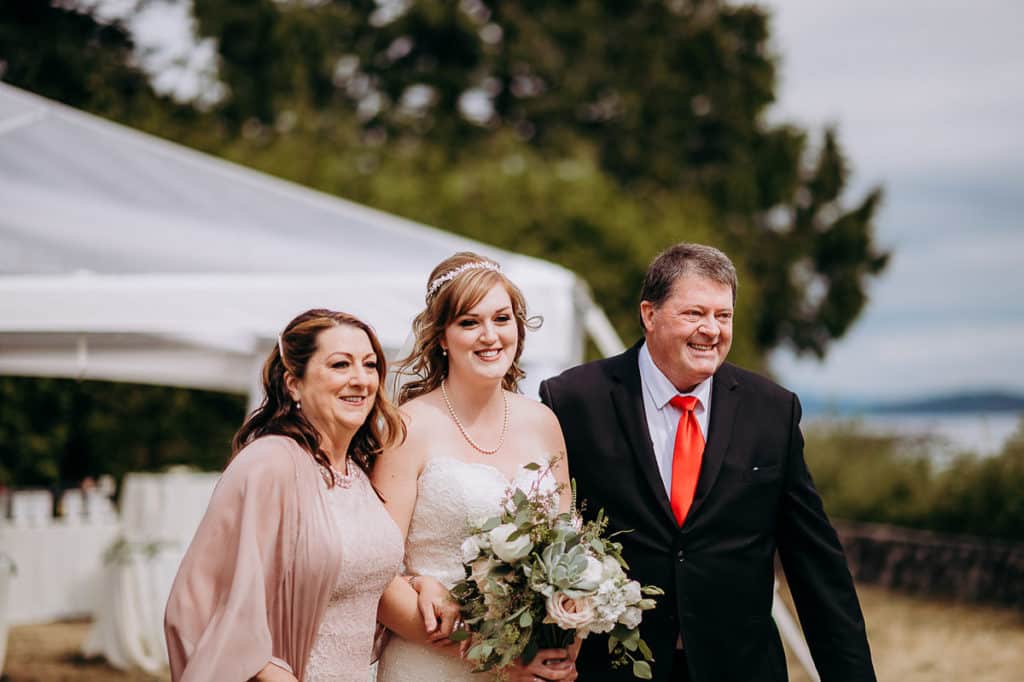 The bride is walked down the aisle with her mother and father Sunshine Coast BC