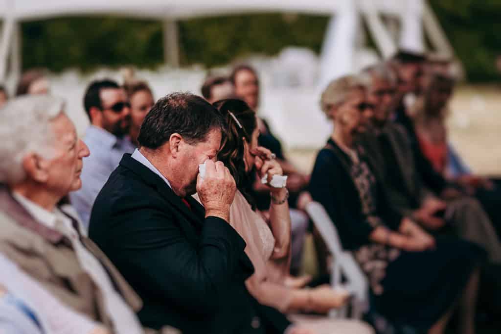 father wipes a tear away at his daughter's wedding