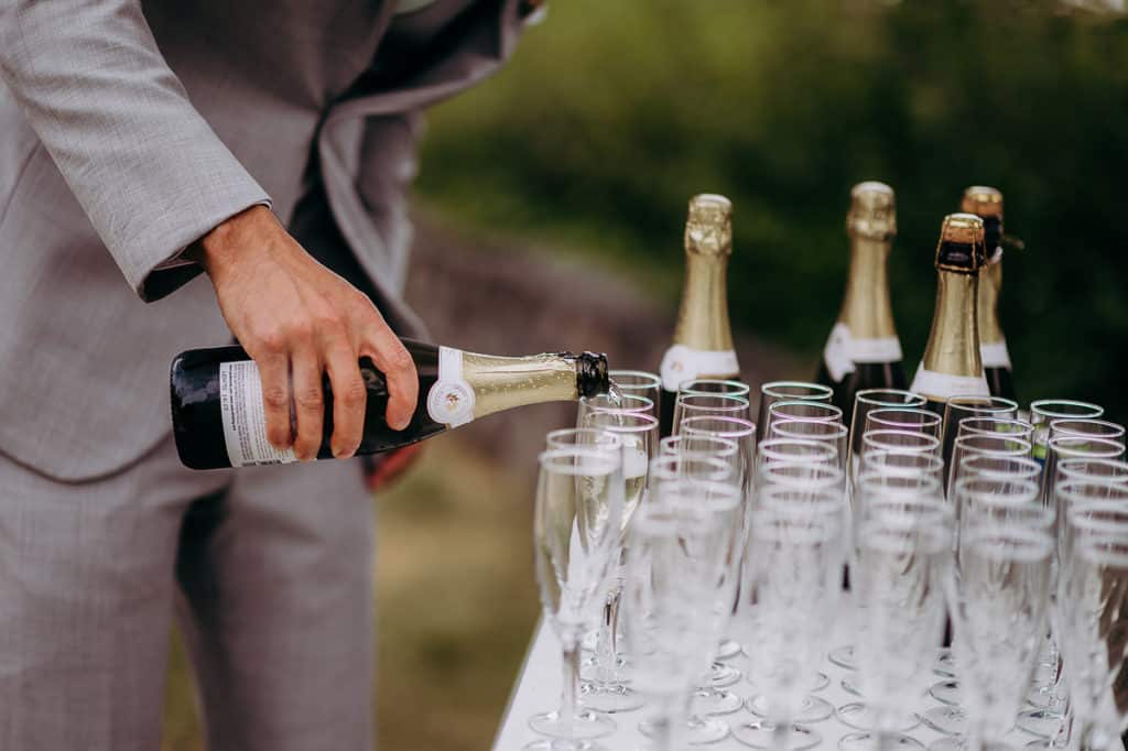 groom pours the glasses of champagne to celebrate wedding in Gibsons BC