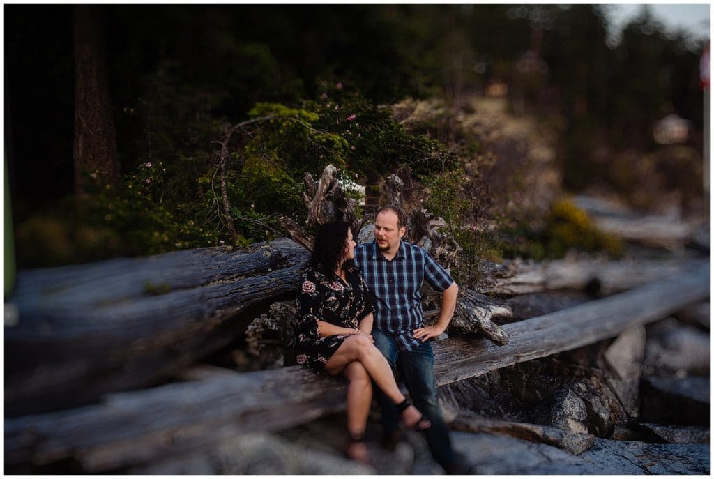 man and woman talk while sitting on a log