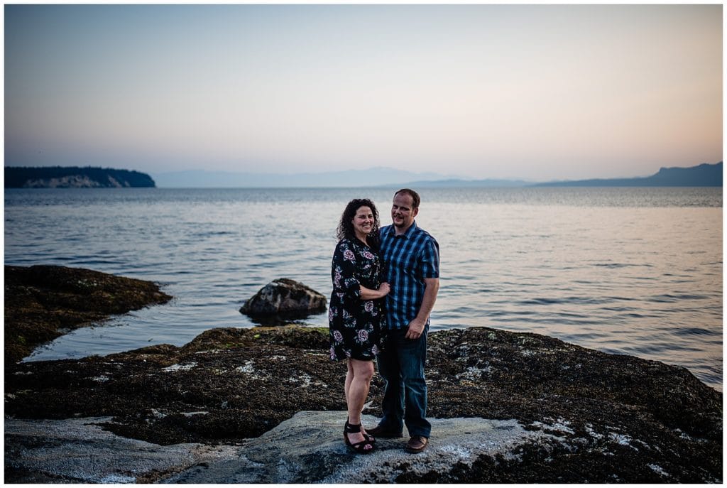 man and woman pose for a portrait on a rocky beach