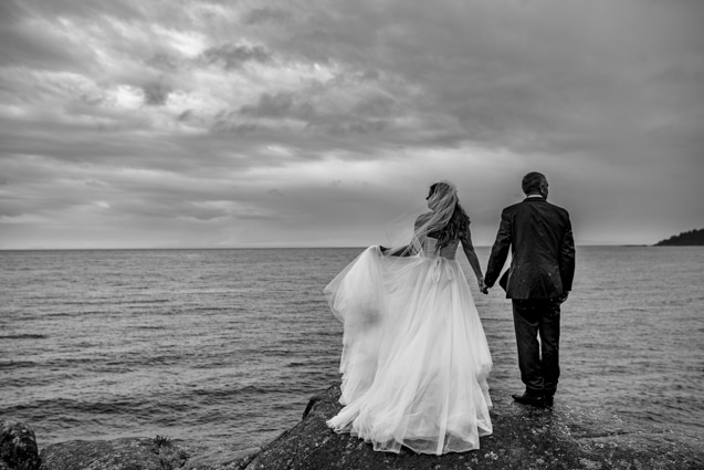 photography pricing for weddings and other sessions with Fresh Air Photography featuring bride and groom standing on rock at the edge of the ocean looking opposite ways.