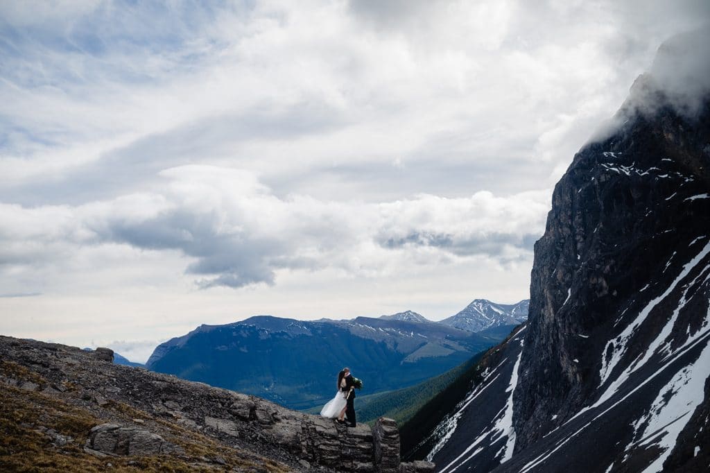 a newly eloped couple embrace where two mountain peaks meet during their adventure elopement in british columbia with bc adventure elopement photographer 
