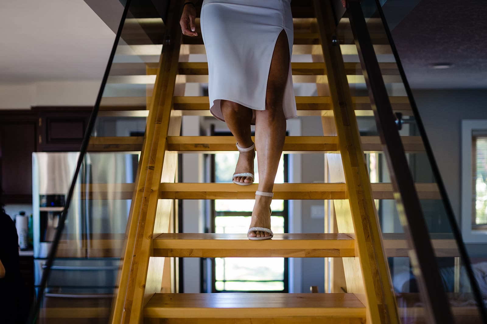 Bride takes some of her final steps as a single woman down the wooden floating staircase before she marries her man