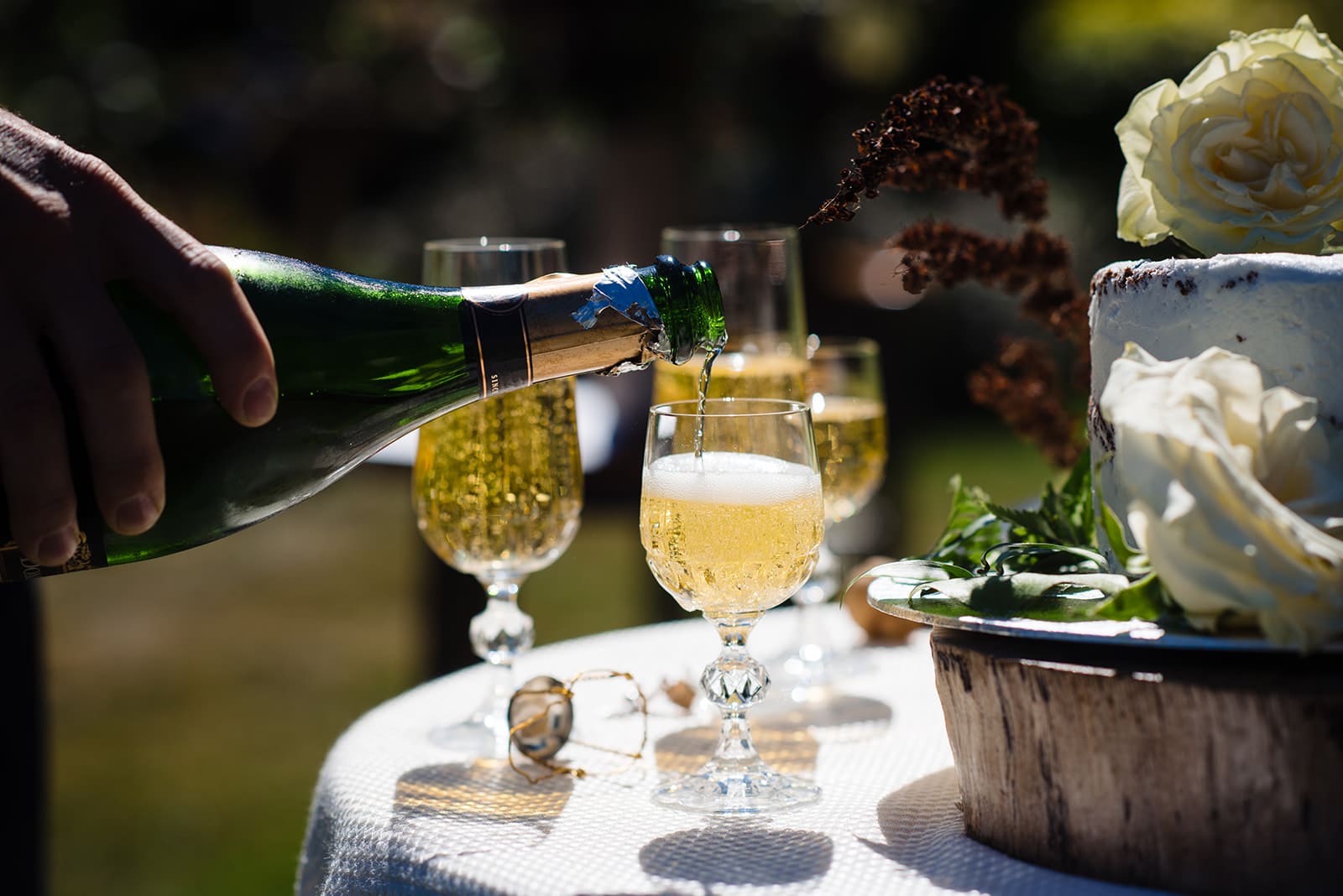 Bottle of champagne is poured into glasses to celebrate two people in love getting married