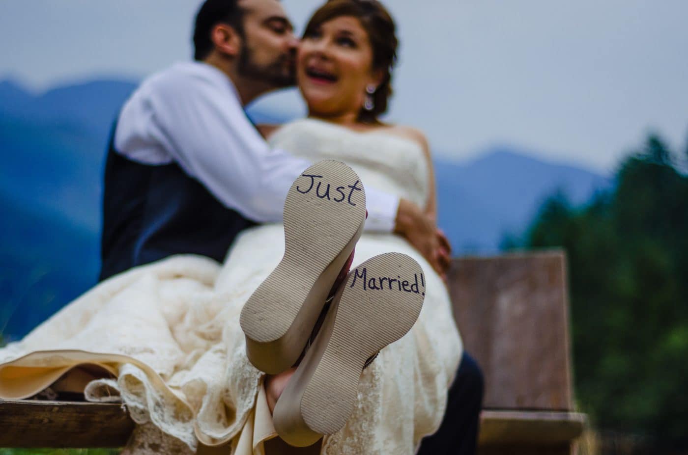 Groom kisses bride with just married notes on bride's shoes