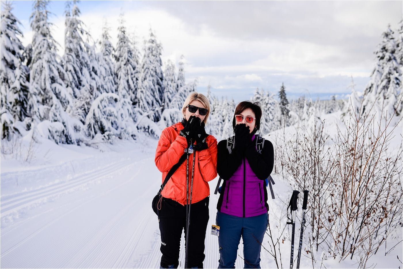 two friends cover their mouths as a joke while snow shoeing