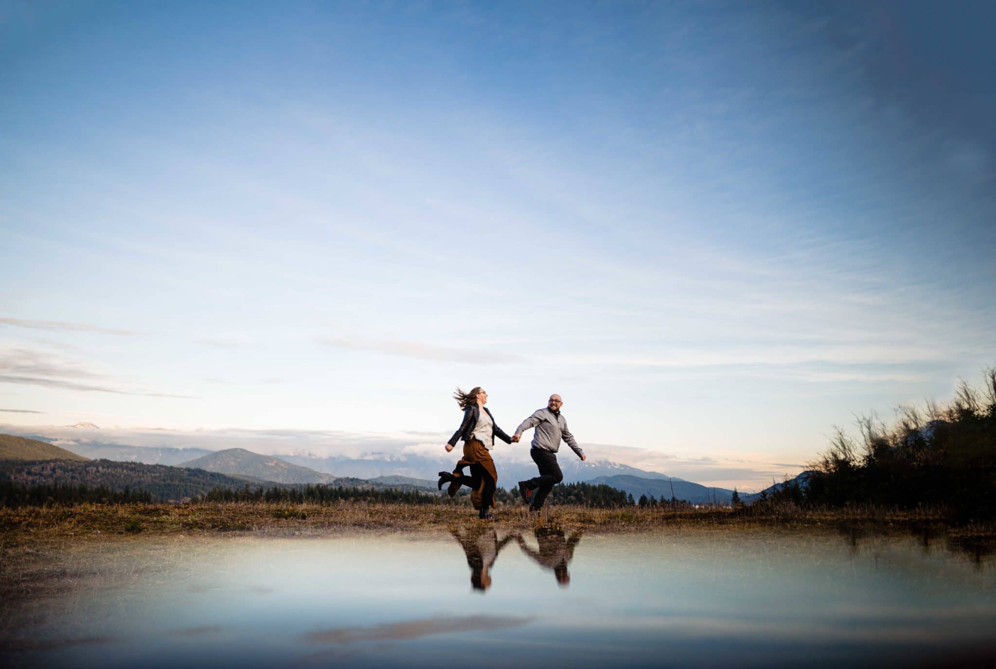 couple run along the mountains in engagement session