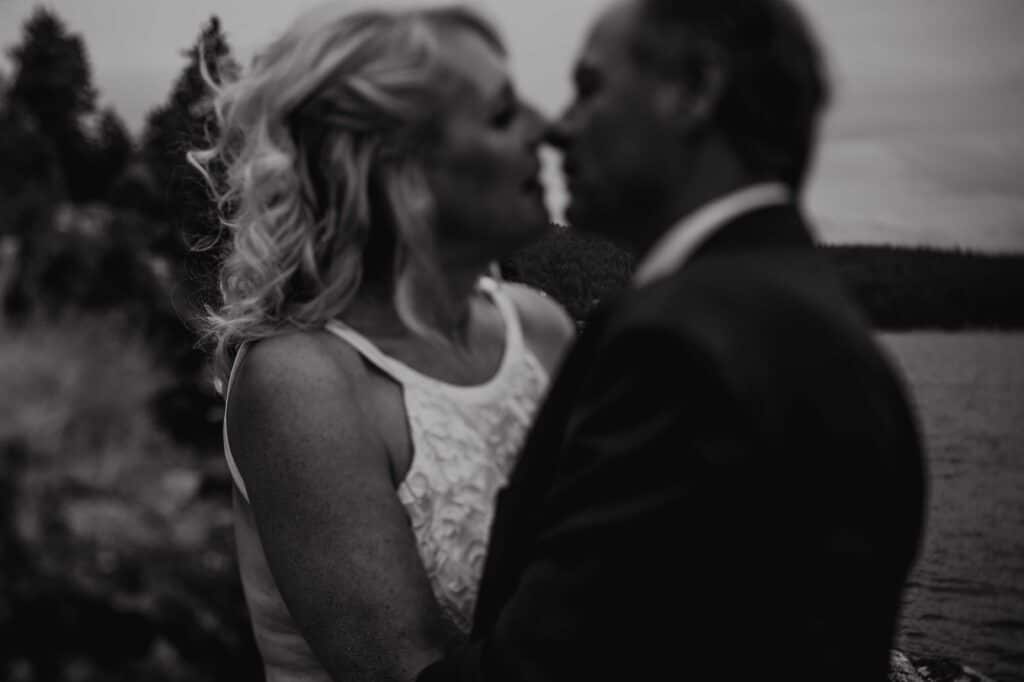 Black and white photo of a bride leaning in to kiss her groom outside their Sunshine Coast wedding venue